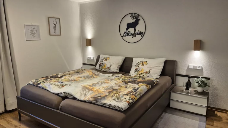 Schlafzimmeraufnahme der Ferienwohnung mit Doppelbett und Wandleuchten an der Seite.